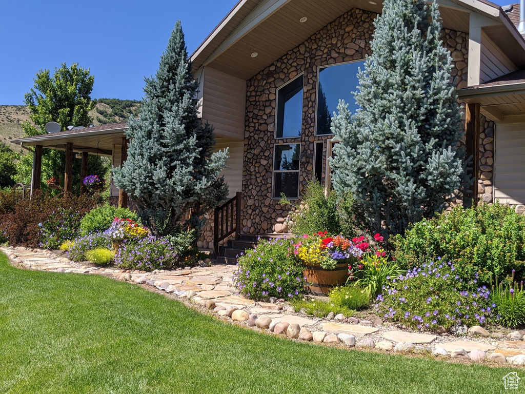 View of side of home featuring stone siding and a lawn