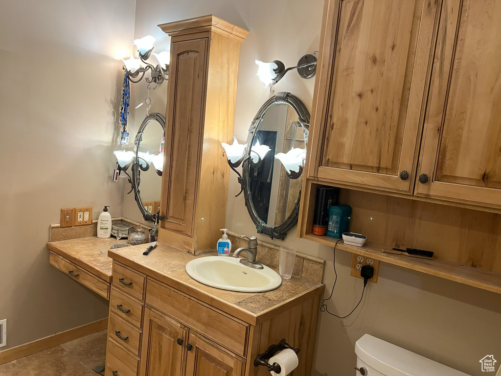 Half bathroom featuring toilet, vanity, and tile patterned flooring