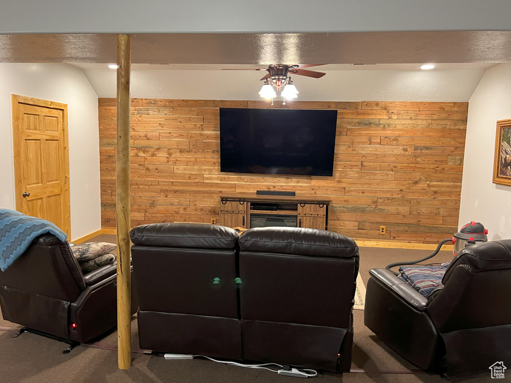 Carpeted living area with wood walls, a ceiling fan, and recessed lighting