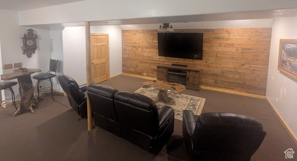 Living room with wooden walls, carpet flooring, and a fireplace