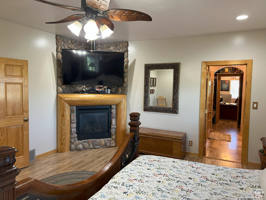 Bedroom with wood finished floors, a stone fireplace, baseboards, and recessed lighting
