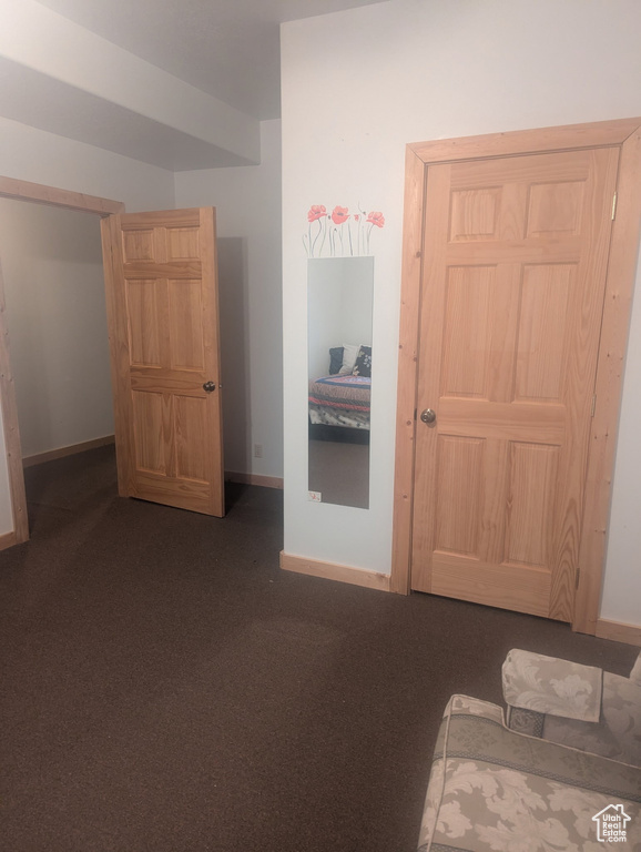 Bedroom featuring dark colored carpet and baseboards