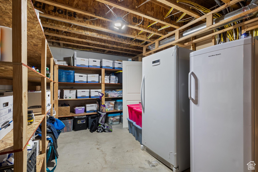 Unfinished basement with refrigerator and freestanding refrigerator