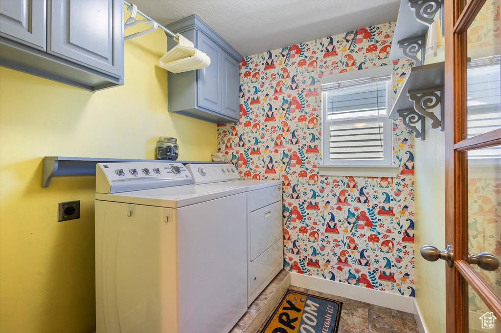 Laundry room with cabinet space, wallpapered walls, baseboards, and washer and clothes dryer