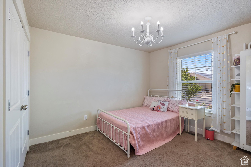Bedroom featuring a chandelier, carpet floors, baseboards, and a textured ceiling