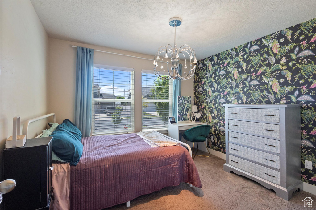 Bedroom featuring wallpapered walls, a chandelier, carpet floors, baseboards, and a textured ceiling