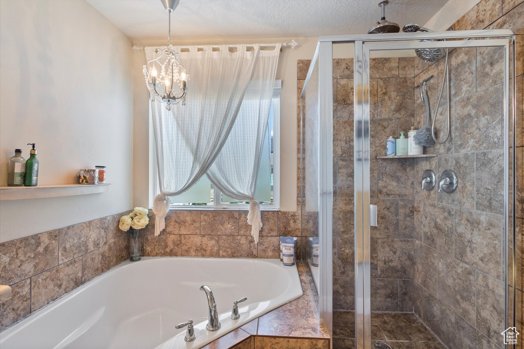 Bathroom with a bath, a stall shower, and a chandelier