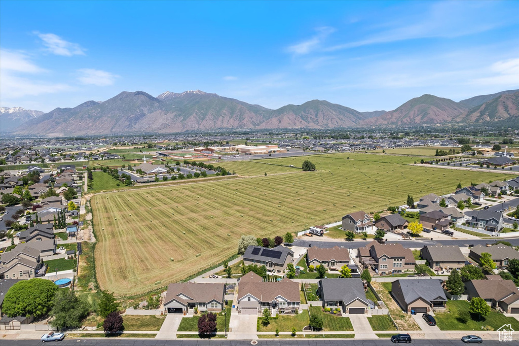 Aerial view of property and surrounding area featuring nearby suburban area and a mountain backdrop