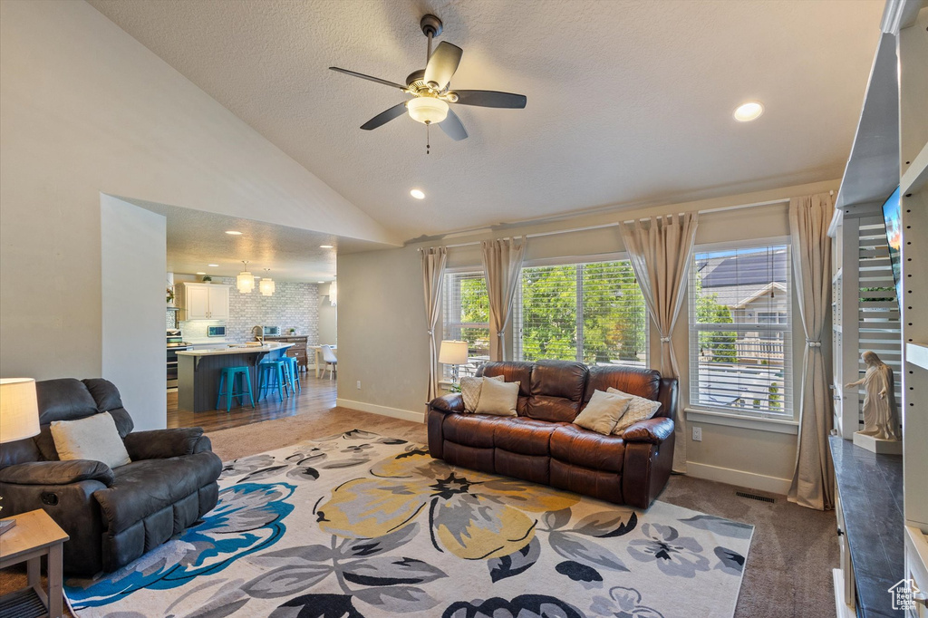 Living area with ceiling fan, baseboards, plenty of natural light, lofted ceiling, and recessed lighting