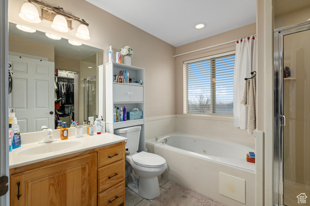 Bathroom featuring a tub with jets, vanity, a shower stall, toilet, and tile patterned floors