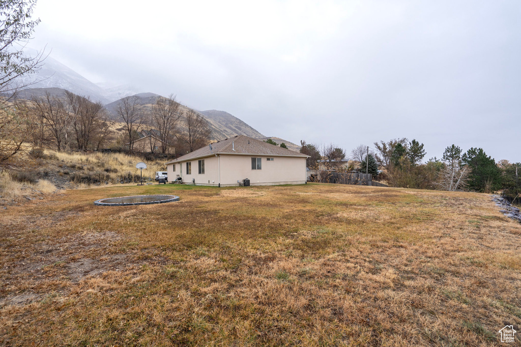 View of grassy yard featuring a trampoline and a mountain view
