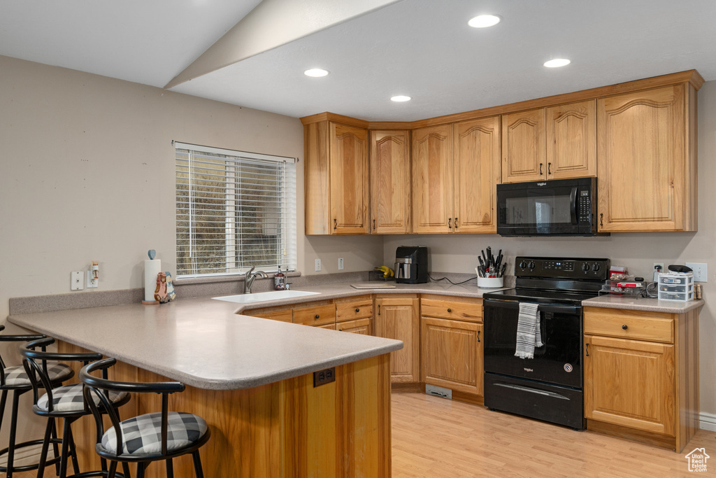 Kitchen with black appliances, a sink, a breakfast bar, a peninsula, and recessed lighting