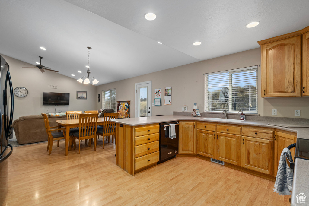 Kitchen featuring a sink, black appliances, open floor plan, vaulted ceiling, and a peninsula