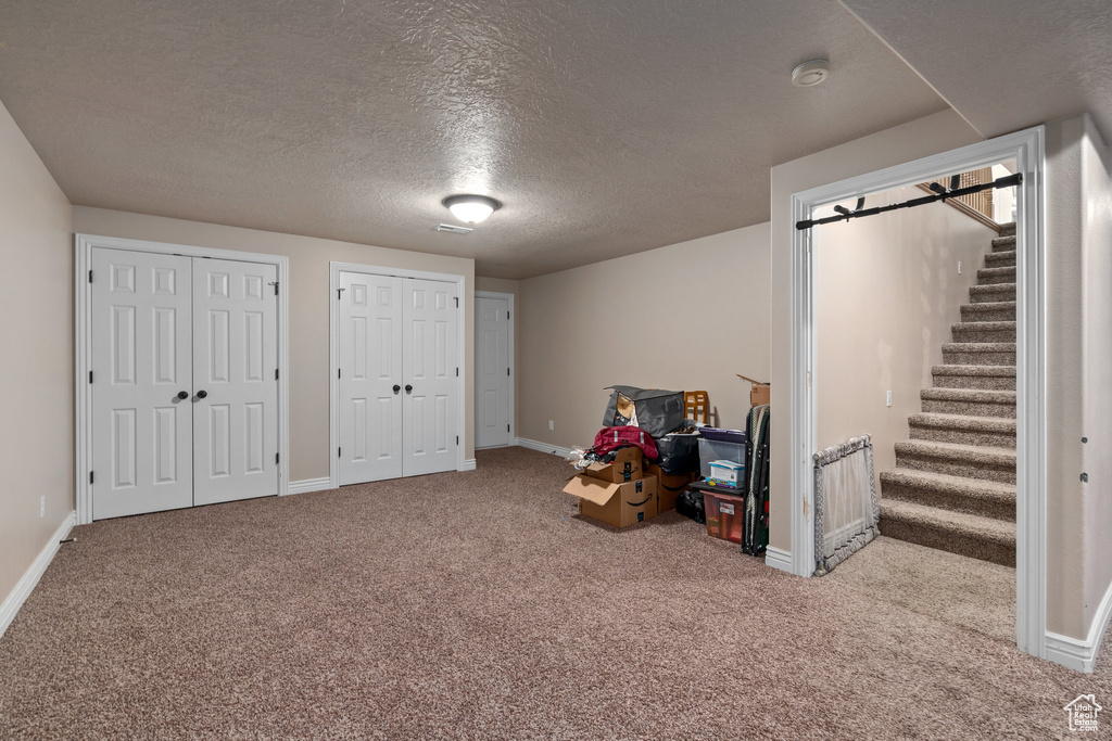 Rec room featuring carpet, a textured ceiling, and baseboards