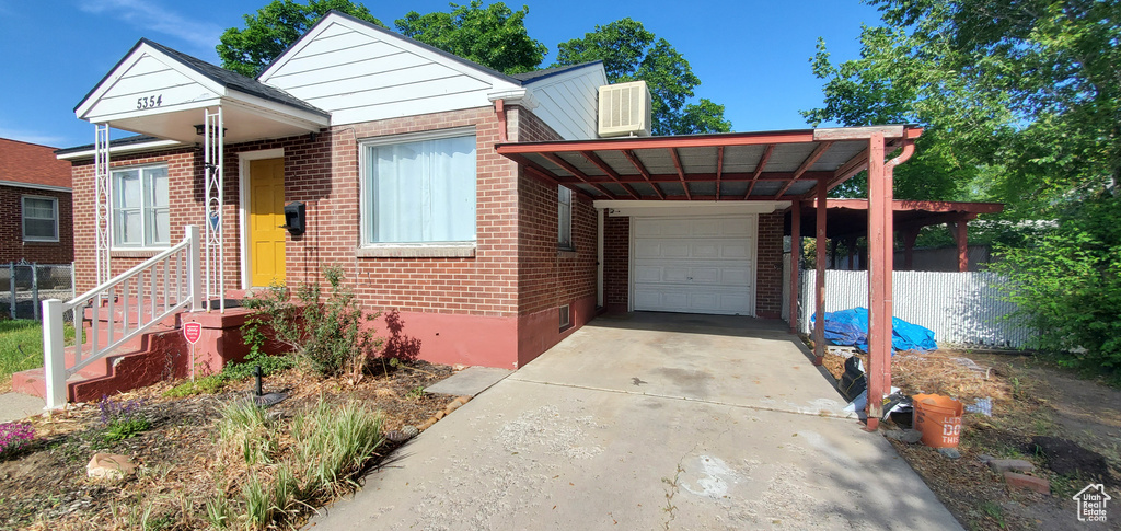 View of front of home with brick siding, driveway, a carport, and an attached garage