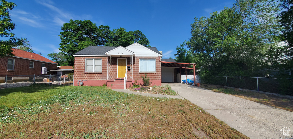 Bungalow-style home featuring brick siding, a carport, and concrete driveway