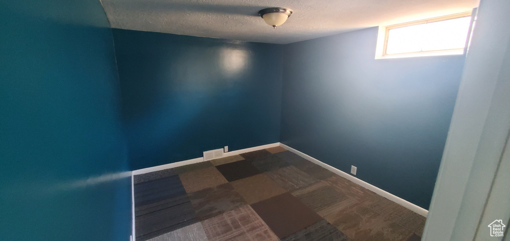 Empty room with a textured ceiling and baseboards