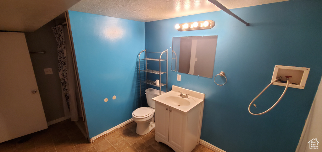 Full bathroom with vanity, toilet, a shower with curtain, a textured ceiling, and baseboards