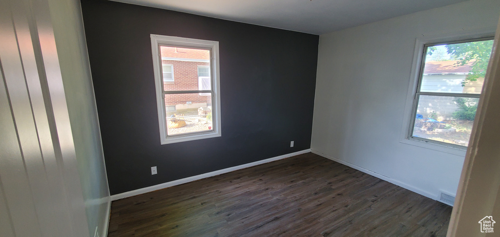 Unfurnished room featuring dark wood-style flooring and baseboards