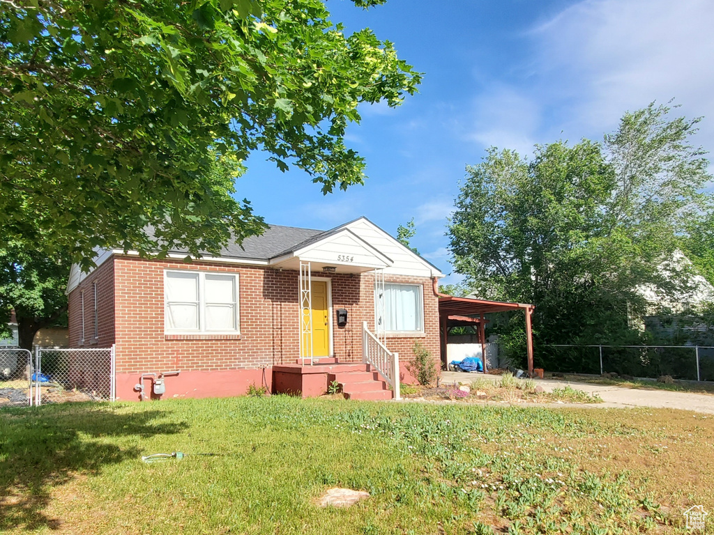 View of front facade with brick siding, driveway, a carport, and a gate