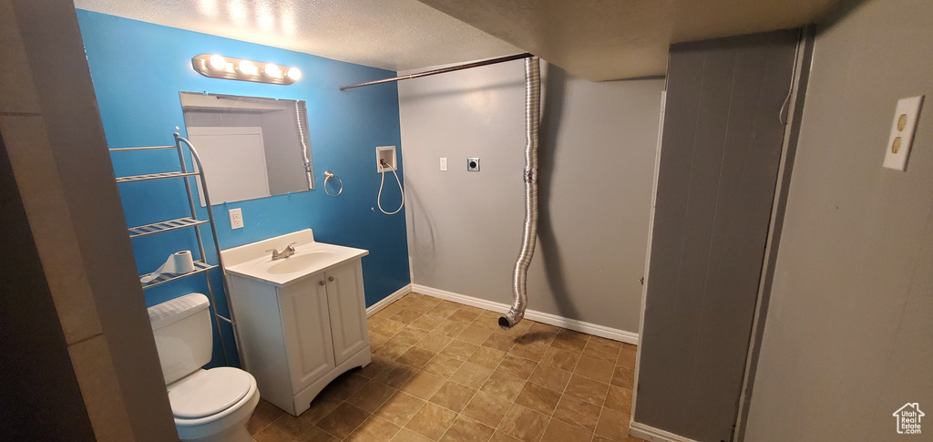Full bath featuring toilet, vanity, baseboards, a textured ceiling, and a shower