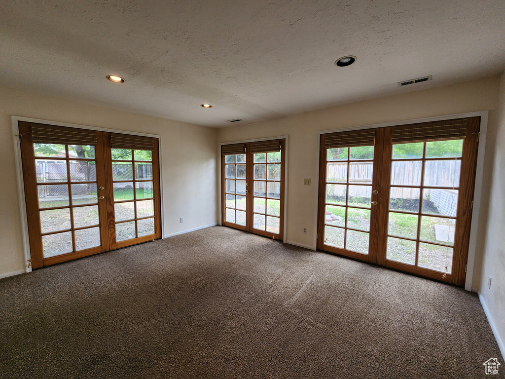 Carpeted spare room featuring french doors, a textured ceiling, recessed lighting, and baseboards