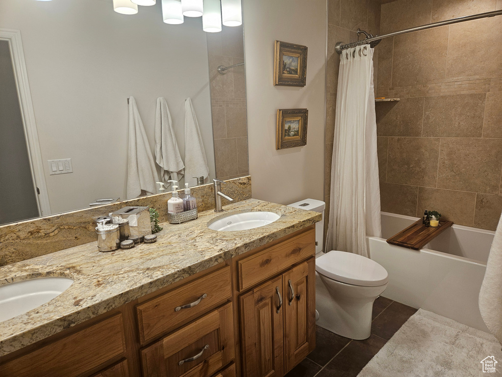 Full bath featuring toilet, shower / tub combo with curtain, double vanity, and tile patterned floors