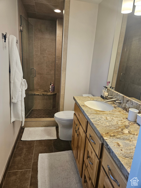 Full bathroom with a stall shower, toilet, double vanity, tile patterned floors, and baseboards