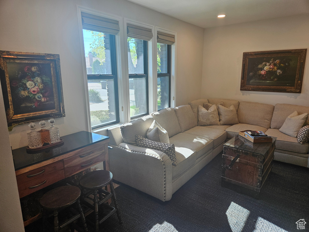 Living area featuring plenty of natural light, dark colored carpet, and recessed lighting