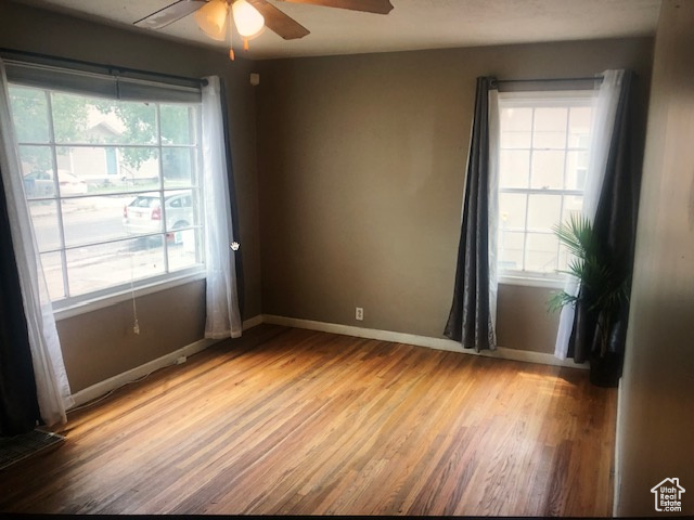Spare room featuring a ceiling fan, healthy amount of natural light, light wood-type flooring, and baseboards