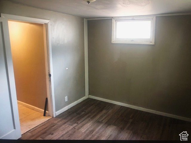 Spare room featuring dark wood-type flooring and baseboards