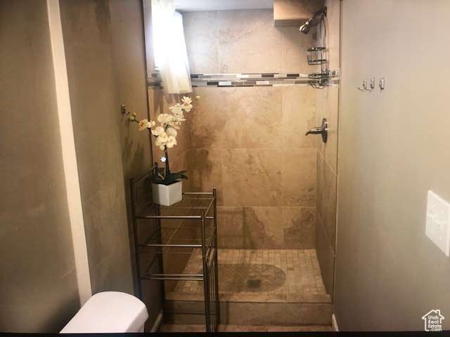 Full bath with tiled shower and toilet