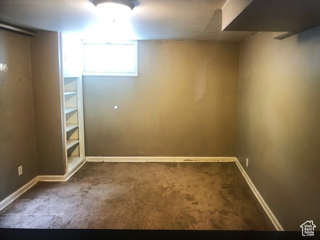 Below grade area featuring dark carpet and baseboards