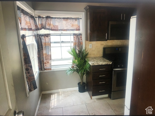Kitchen with stainless steel range, baseboards, dark brown cabinets, and light tile patterned flooring