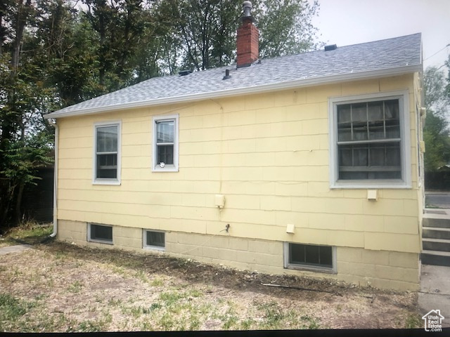 View of side of property with a shingled roof and a chimney