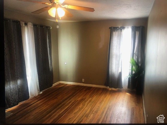 Spare room with wood finished floors, ceiling fan, and baseboards