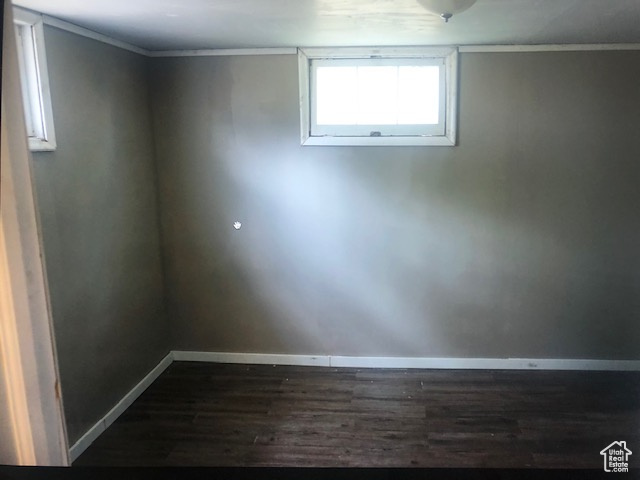 Below grade area featuring dark wood-style flooring, baseboards, and ornamental molding
