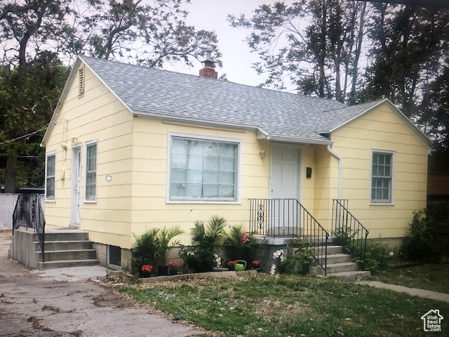 Bungalow-style house with a shingled roof and a chimney