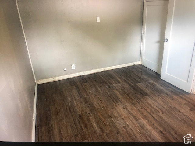 Unfurnished room featuring dark wood-type flooring and baseboards