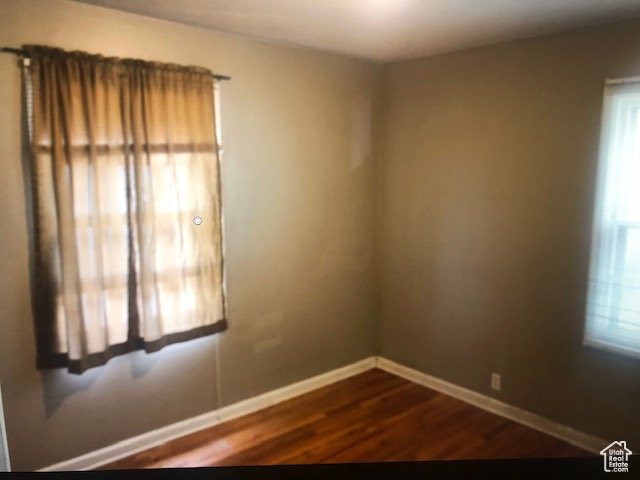 Spare room with baseboards and dark wood-style flooring