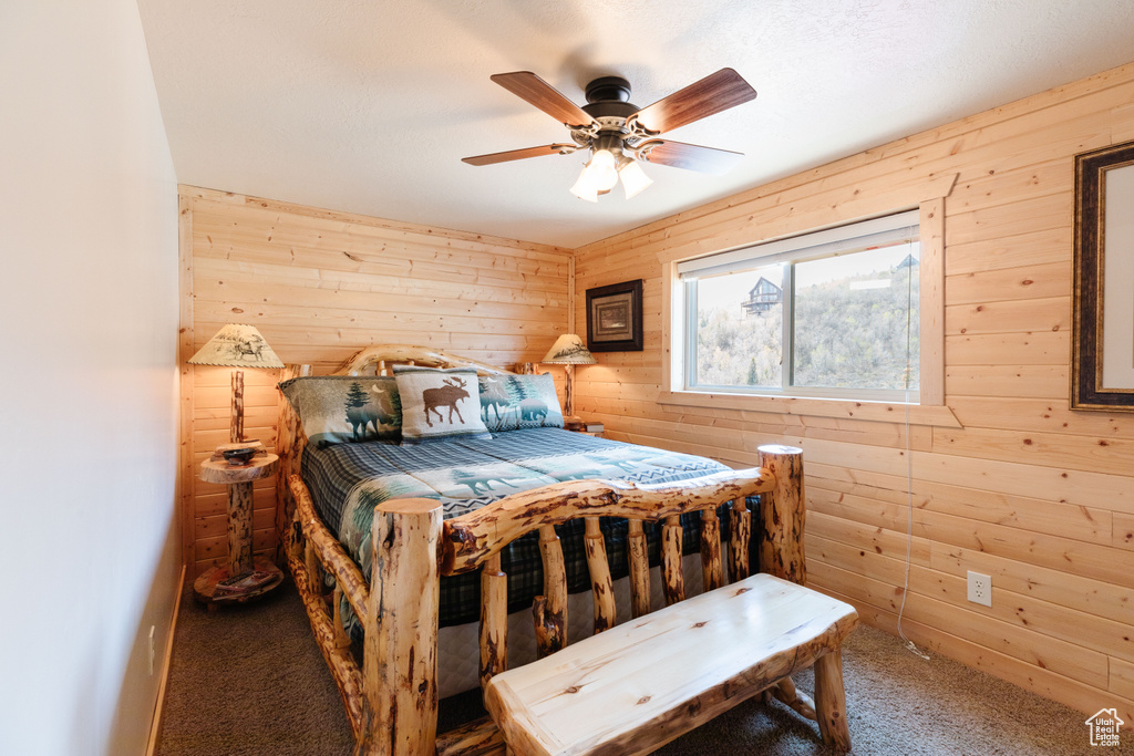 Bedroom with carpet, wooden walls, and a ceiling fan