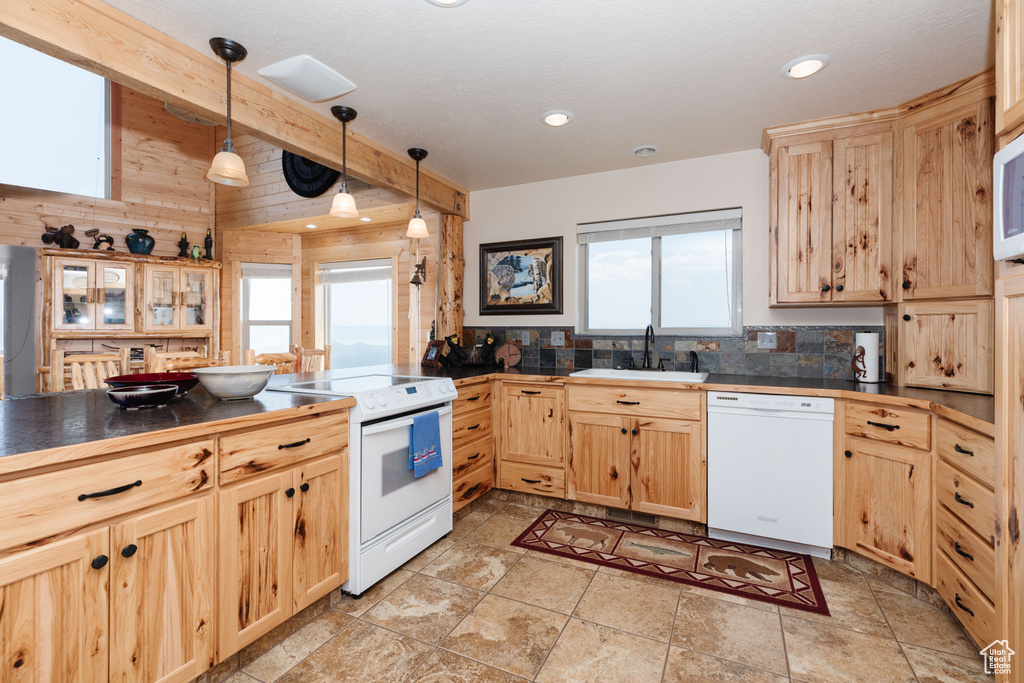 Kitchen with white appliances, a sink, light brown cabinets, dark countertops, and recessed lighting