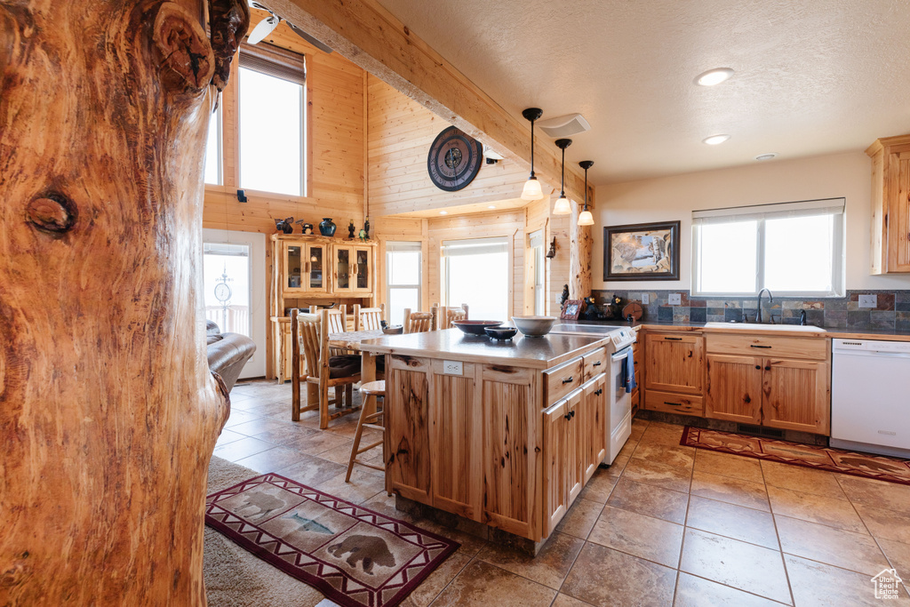 Kitchen featuring white appliances, a kitchen breakfast bar, a sink, a peninsula, and hanging light fixtures