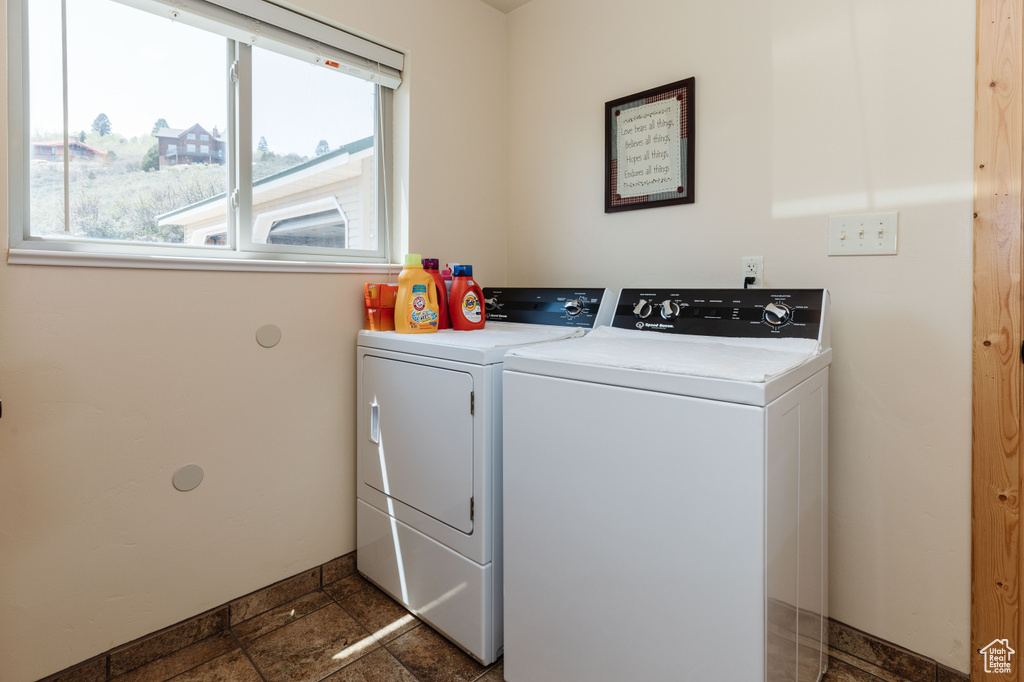 Washroom featuring washer and clothes dryer, stone tile flooring, and baseboards