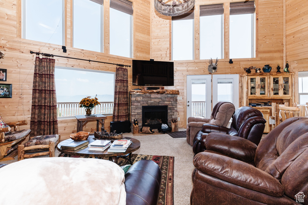 Living room with wooden walls, a high ceiling, carpet floors, a fireplace, and french doors
