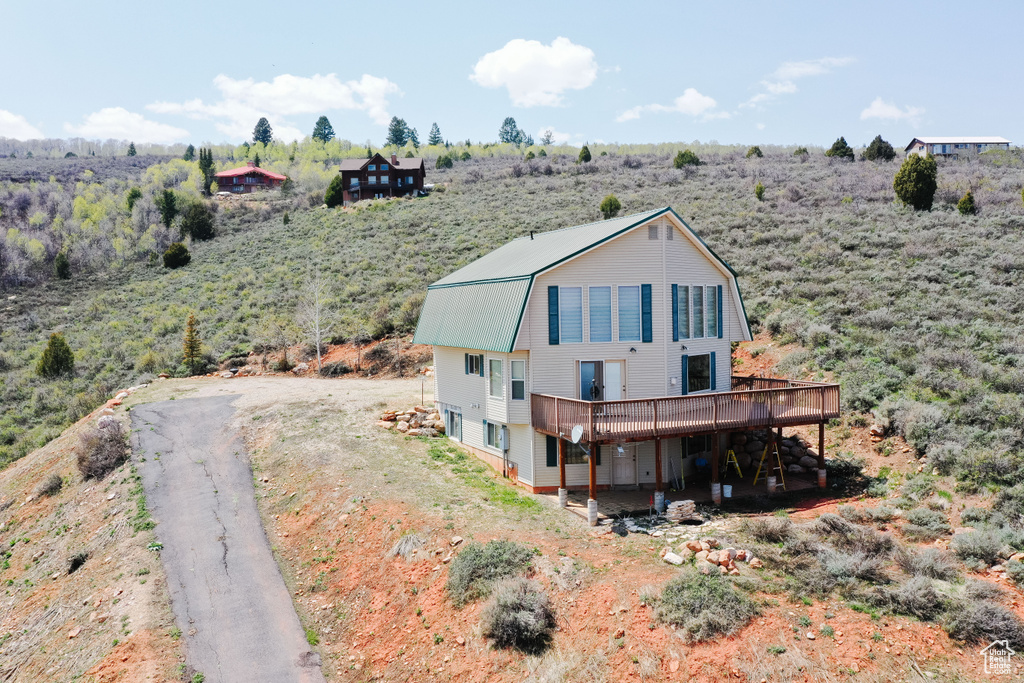 View of front of home featuring a gambrel roof, a deck, metal roof, and a view of countryside