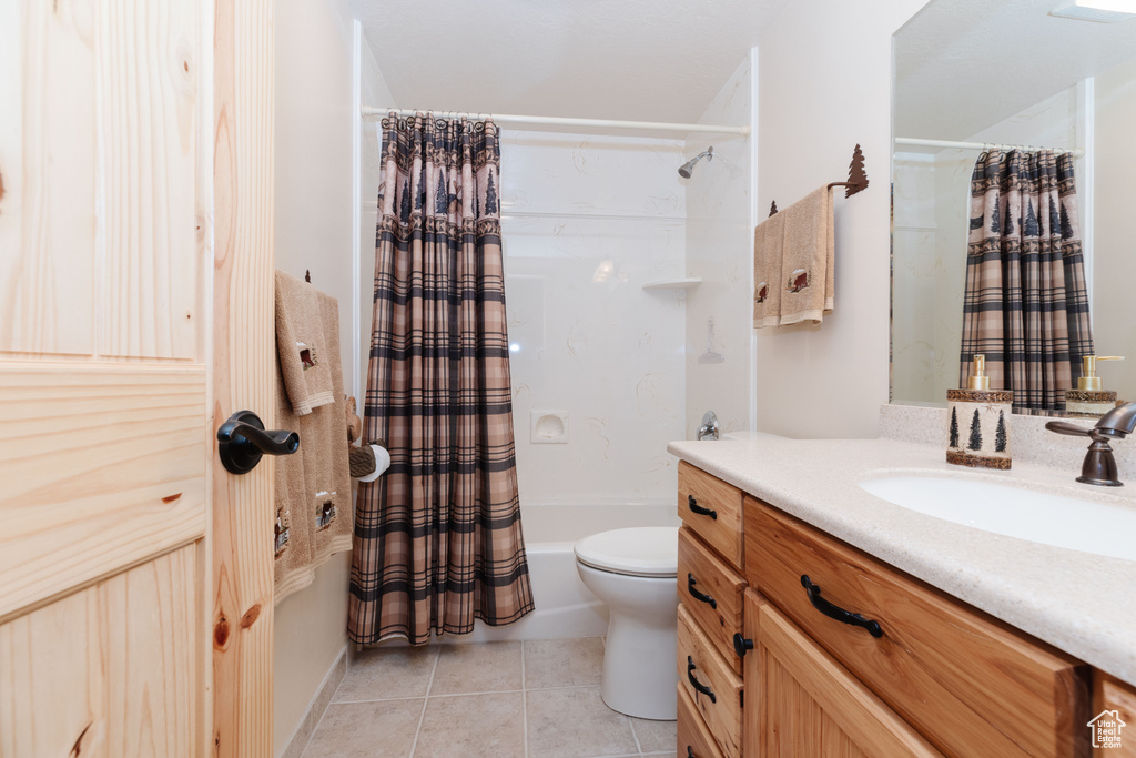 Bathroom featuring vanity, tile patterned flooring, shower / tub combo, and toilet