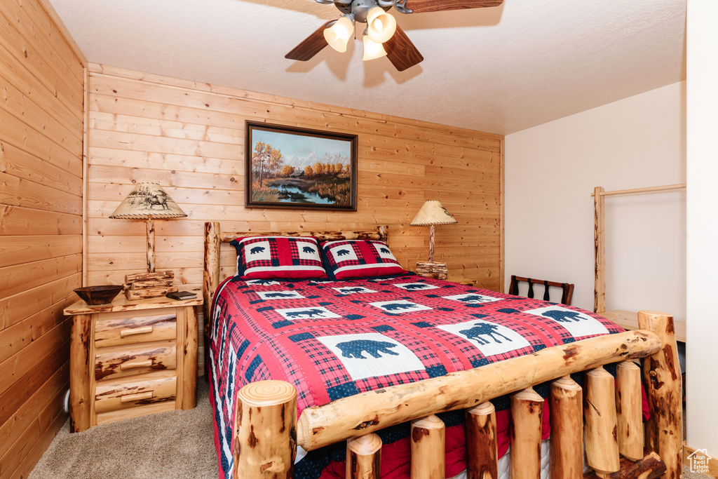 Carpeted bedroom featuring wooden walls and a ceiling fan