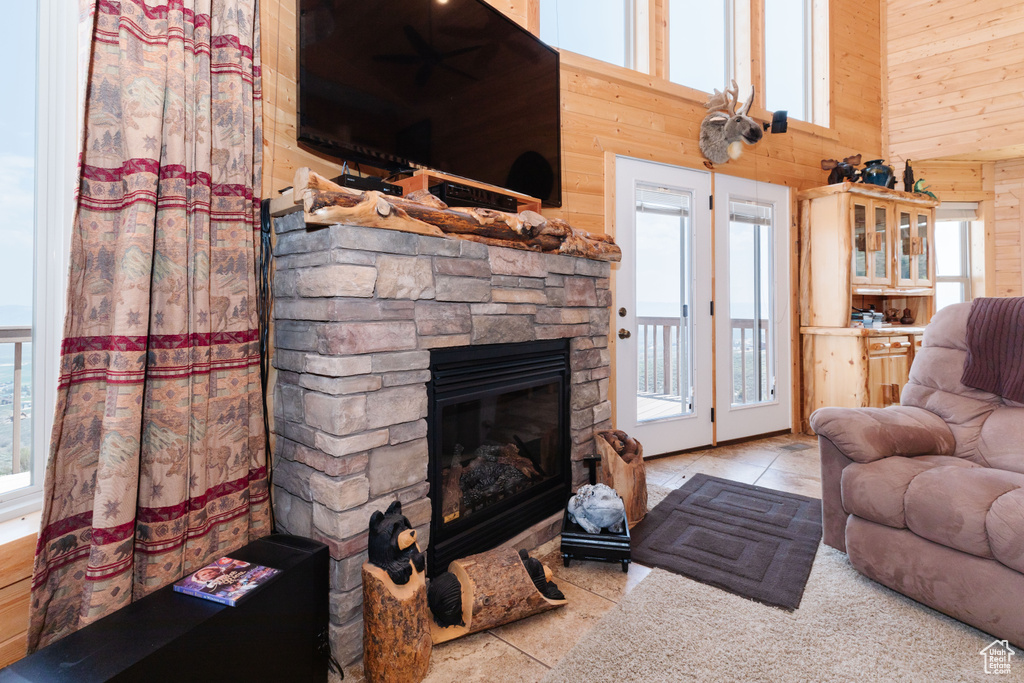 Tiled living room with wood walls, a fireplace, and a high ceiling