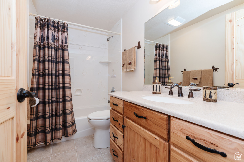 Full bath featuring vanity, tile patterned flooring, shower / tub combo with curtain, and toilet